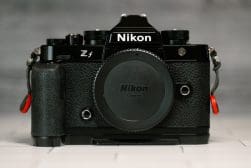 A Nikon Zf camera without a lens, displayed on a table, showcasing its front view with a black body and grip.