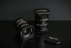 Two camera lenses with caps display aperture and focal length markings, set against a dark background.