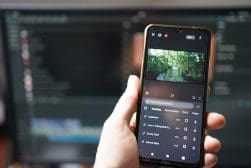 A hand holds a smartphone displaying a nature trail photo on a social media app, with icons visible beneath the image.