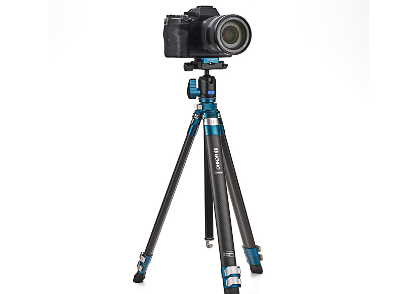 A black DSLR camera mounted on a blue and black tripod against a white background.