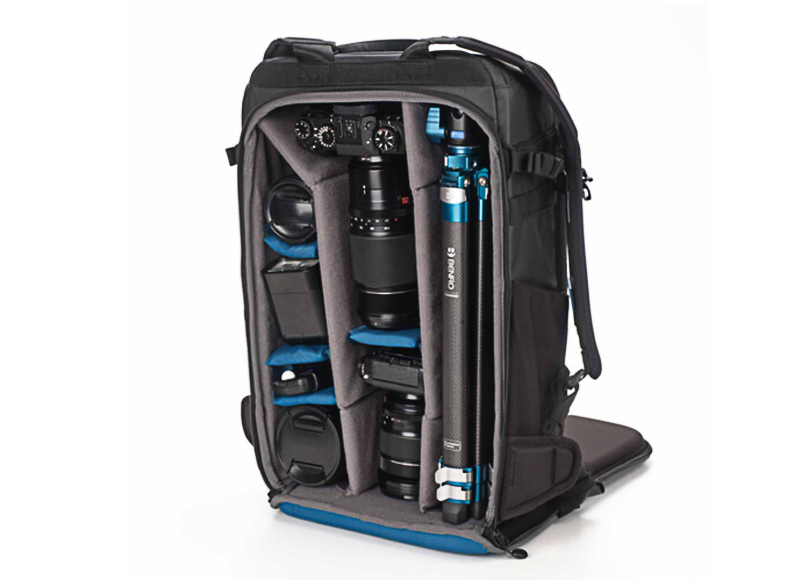 A camera backpack with organized compartments holding a camera, multiple lenses, and a tripod.