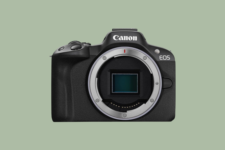 A Canon EOS camera body without a lens, shown on a plain green background.