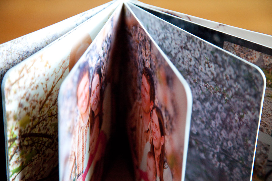 A photo book opened to a middle page, displaying several colorful images of people in an outdoor setting.