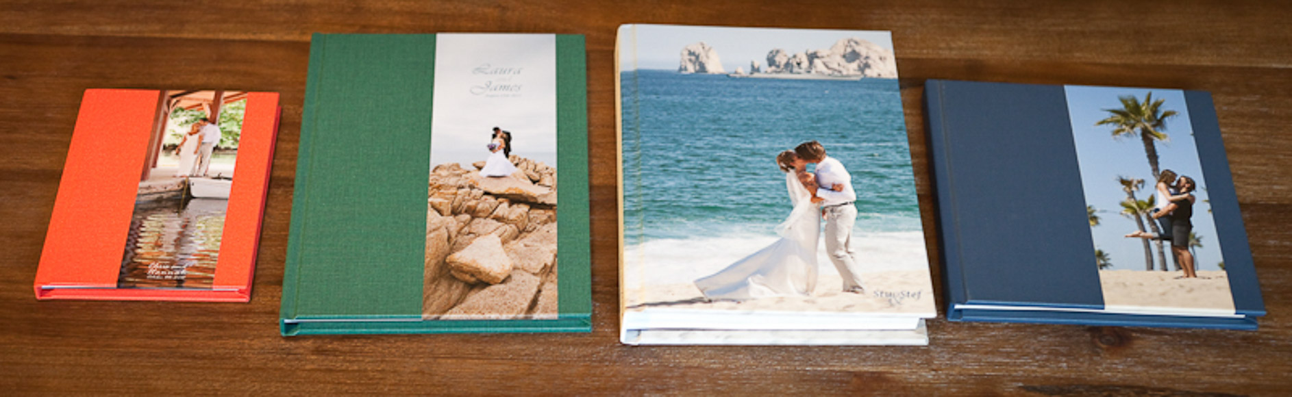 A row of five photo albums with different sizes and cover images, including couples and wedding scenes, displayed on a wooden surface.