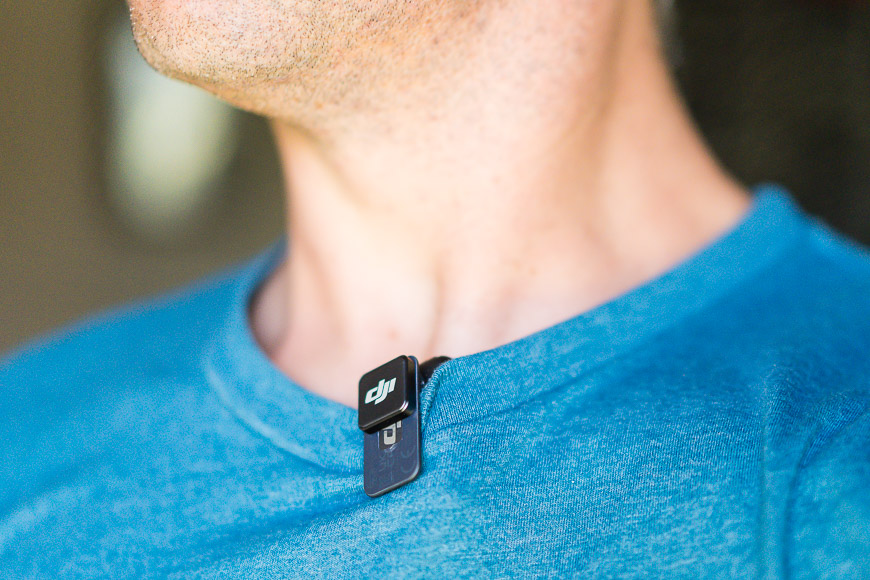 A small black device clipped to the collar of a person's blue shirt.