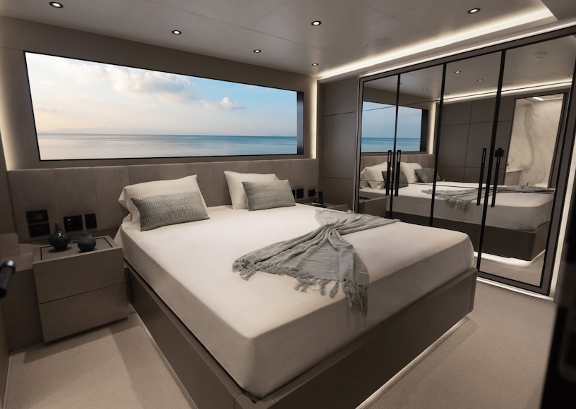Modern bedroom with a large bed, gray bedding, and a window view of the sea. A mirrored wardrobe is on the right, creating a spacious feel in the well-lit room.