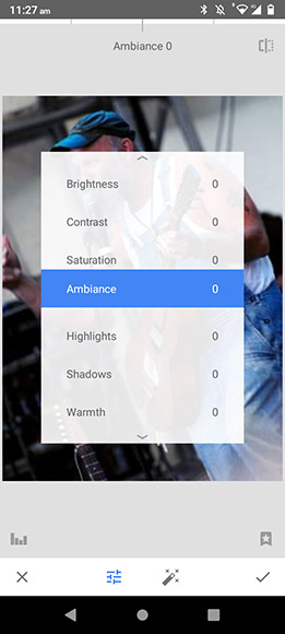 A photo editing app interface displaying adjustment options for brightness, contrast, saturation, ambiance, highlights, shadows, and warmth, all set to zero. Background shows a person with a guitar.