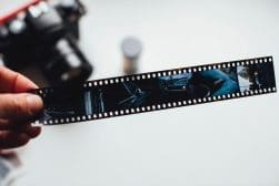 A person holding a film strip with a camera.