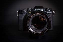 A Fujifilm X-T5 camera with a 56mm f/1.2 R Fujinon aspherical lens attached, set against a dark background.