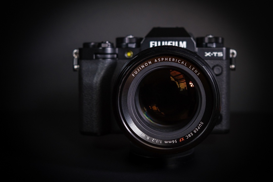 A Fujifilm X-T5 camera with a 56mm f/1.2 R Fujinon aspherical lens attached, set against a dark background.
