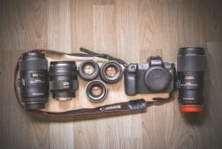 A Canon EOS R camera with multiple interchangeable lenses and accessories laid out on a wooden surface.