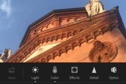 An ornate, red-brick building with statues and detailed carvings is shown from a low angle. Editing tools are visible at the bottom of the image.