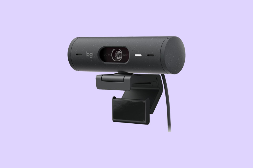 A black webcam with a cylindrical design and a clip attached, set against a light purple background.