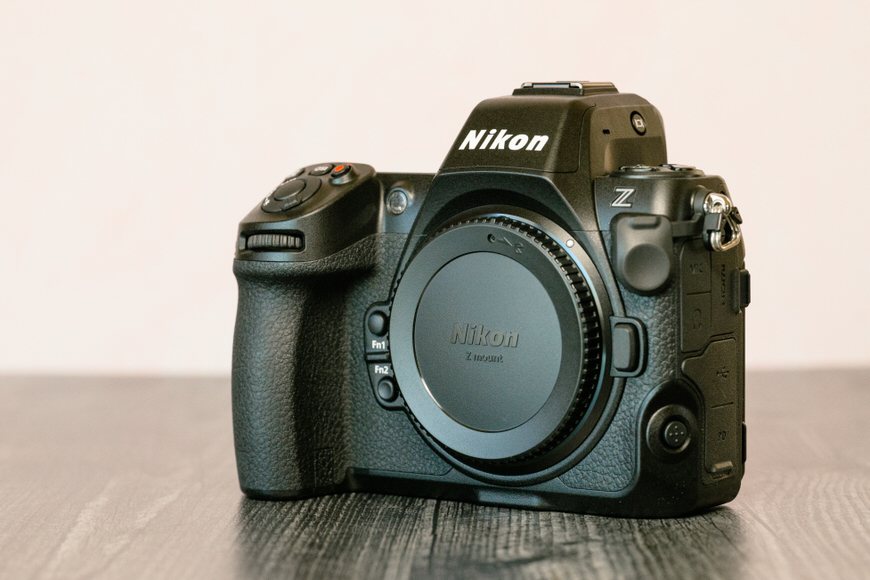 A Nikon Z series mirrorless camera with a cap on the lens mount, placed on a wooden surface.