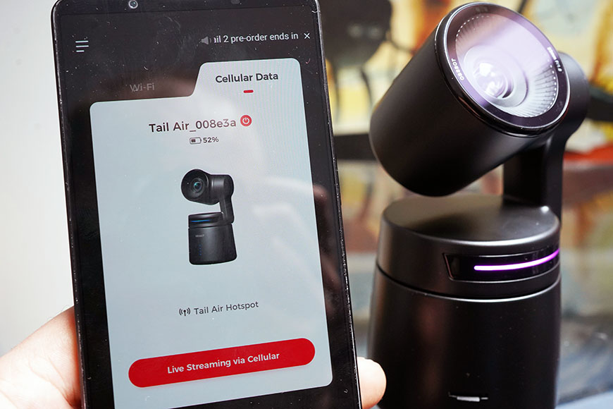 Smartphone displaying a live streaming app connected to a black rotating camera device.