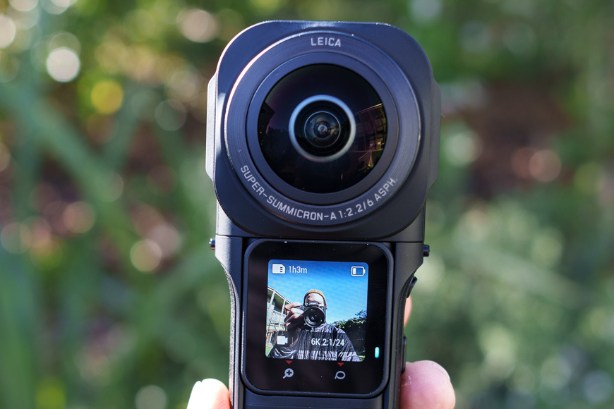 A person is holding up a camera with a lens on it.