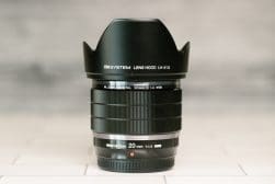 The OM System 20mm f/1.4 lens sitting on top of a tiled floor.
