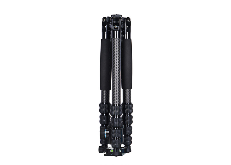 A folded black and silver tripod with foam grips and adjustable legs in a collapsed position against a plain white background.