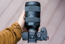 A hand holding a sony camera with a tamron lens.