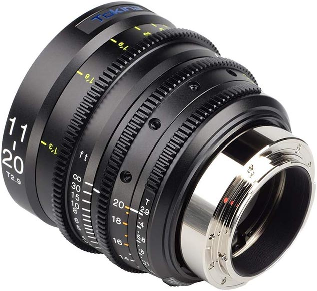 Close-up of a Tekina camera lens with various focus and aperture adjustments, shown from an angle highlighting its metal mount and engraved measurement markings.