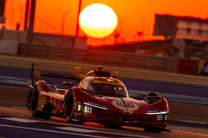 Race car number 50 speeding on the track at sunset.