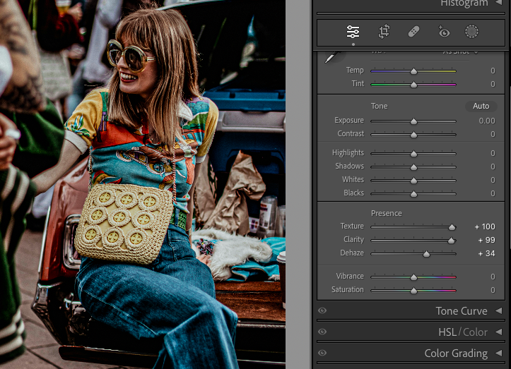 A person wearing sunglasses and colourful shirt sits on a surface with a textured beige bag, next to a window with photo editing sliders visible.