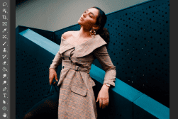 A person posing in a plaid dress against a backdrop with geometric shapes.